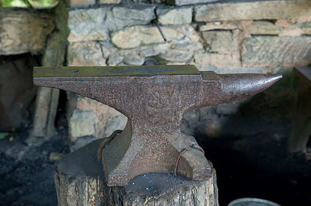铁砧，铁锈附着在树桩上，背景为石墙