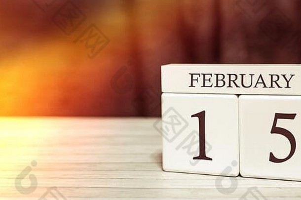 日历提醒事件概念。2月15日，阳光照射下，带数字和月份的木制立方体。