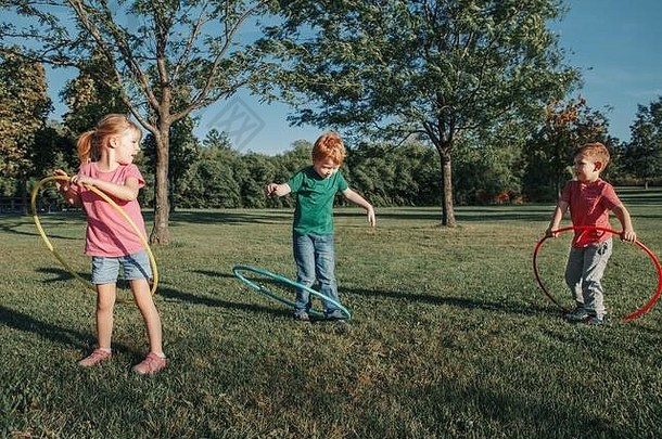 可爱微笑的白人学龄前男女朋友在公园外玩呼<strong>啦</strong>圈。儿童体育<strong>活动</strong>。生活方式快乐童年。夏季海洋