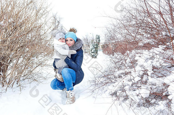 母亲和小女儿在冬季公园散步。幸福家庭。童年和为人父母的幸福。第一场雪。