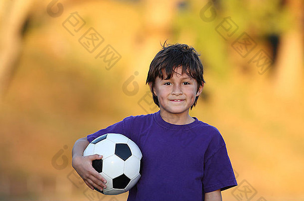 日落时，年轻男孩拿着足球的肖像，美丽的金色秋叶模糊的背景和左侧的空间