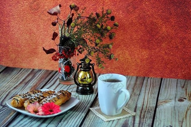 温暖的秋天静物画，一杯热<strong>茶</strong>，一个盛着三个冰壶的盘子和一个有植物标本室的玻璃花瓶。特写。