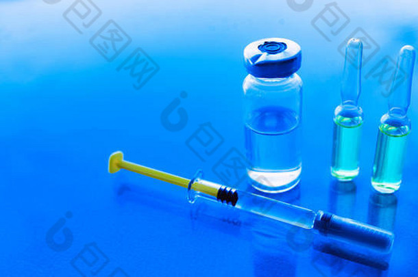 蓝色背景上的注射器、药瓶。疫苗接种概念