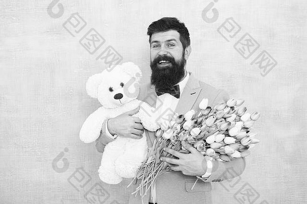 幸福和相爱。大胡子男士西装领结，泰迪熊和花束。给她带来浪漫惊喜的绅士。绅士的浪漫礼物。生日祝福。生日快乐，我的爱人。