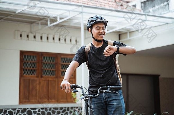 亚洲年轻人站在<strong>折叠自行车</strong>旁看手表