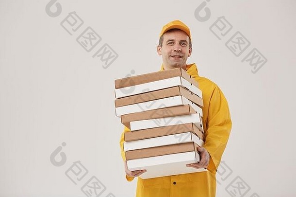 成人送货员举着比萨饼盒，站在白色背景下，对着镜头愉快地微笑，齐腰向上的肖像
