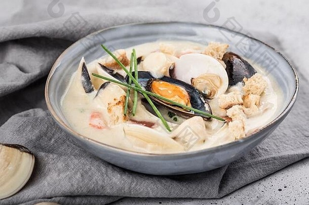 灰色盘子里的蛤蜊杂烩汤。主要成分是贝类、肉汤、黄油、土豆和洋葱。新英格兰汤也被称为波士顿蛤蜊汤