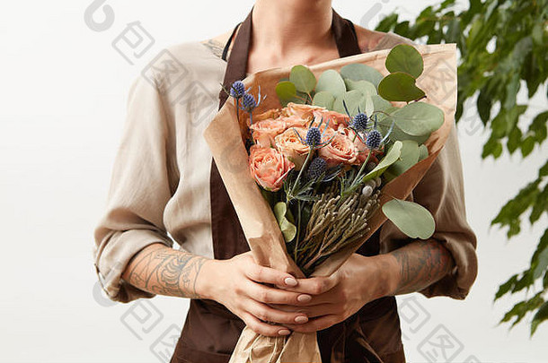 有纹身的女人手拿着玫瑰花束，在浅色背景上表示祝贺，放着文字。贺卡的概念。
