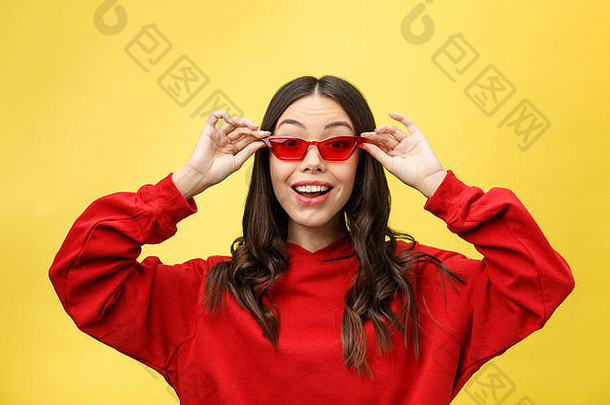 美丽快乐的女人戴着红色太阳镜，背景是五颜六色的