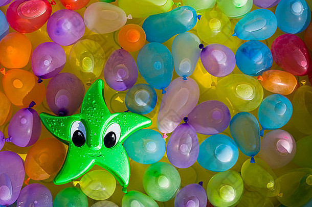 绿色玩具明星，眼睛漂浮在装满水的彩色气球之间