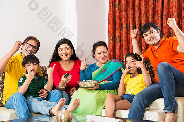 快乐的一家人在家看电视板球比赛庆祝成功
