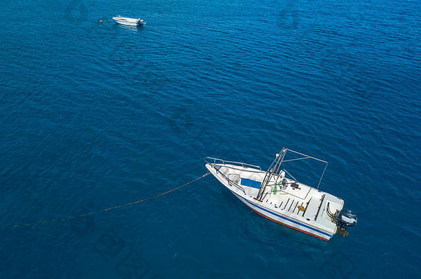 一艘停泊在透明海面上的船的鸟瞰图。潜水放松和暑假。意大利海岸、海滩和岩石