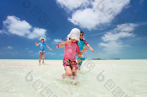 妈妈和孩子们在加勒比海度假，在浅水区跑步