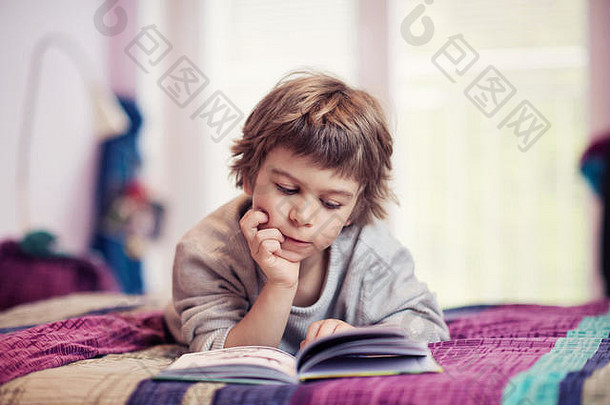 可爱的小男孩躺在床上看书