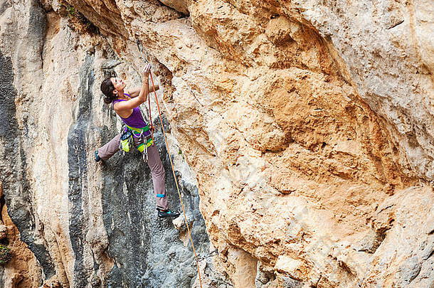 年轻的女岩石登山者突出悬崖