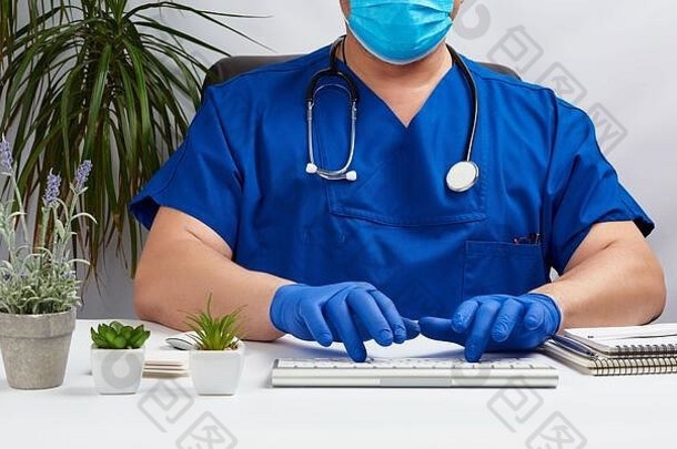 男医生坐在白色的桌子旁，穿着蓝色制服，戴着乳胶手套，专家在键盘上打字，医务室接待病人