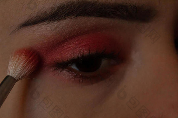 年轻的女人把化妆眼睛明亮的粉红色的眼睛影子化妆刷