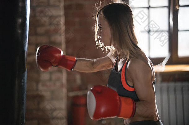 一名好斗的女子拳击手在训练时在健身房击打拳击袋