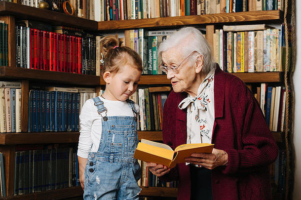 与曾祖母共度快乐时光，老太太与曾孙女共度美好时光。书架前的肖像，谈论书籍