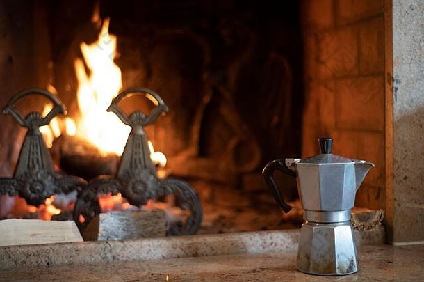 冬天，壁炉旁的意大利咖啡壶里放着一堆燃烧着的旧壁炉，在一个开放的壁炉里近距离观察着