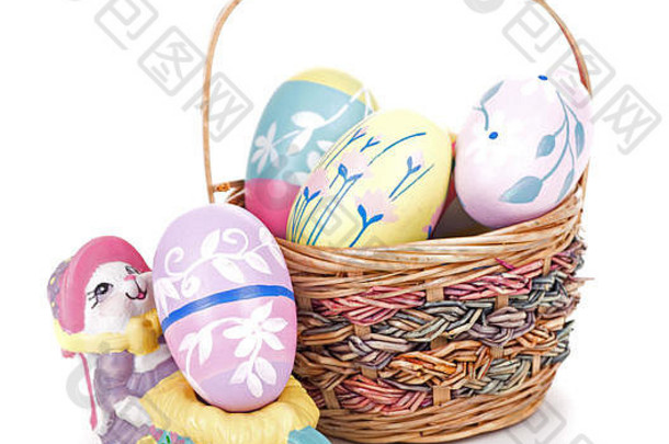 一篮彩色复活节彩蛋和白色背景上的兔子雕像