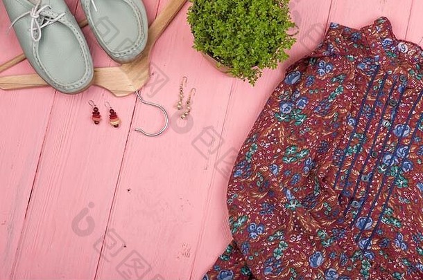 时尚潮流-印花连衣裙、鞋子、衣架、花朵和粉色木桌上的耳环