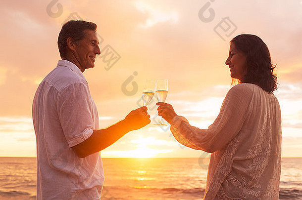 日落时分，一对幸福的浪漫情侣在海滩上享受着一杯香槟。假期旅行退休<strong>周年庆</strong>典。