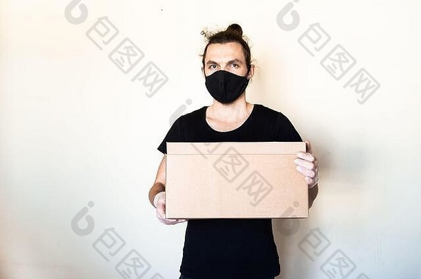快递男人。黑色的脸面具手套持有纸板盒子交付服务检疫流感大流行冠状病毒
