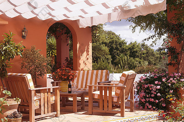 西班牙别墅，露台上有白色遮阳篷，木制<strong>椅子</strong>和沙发上有条纹靠垫