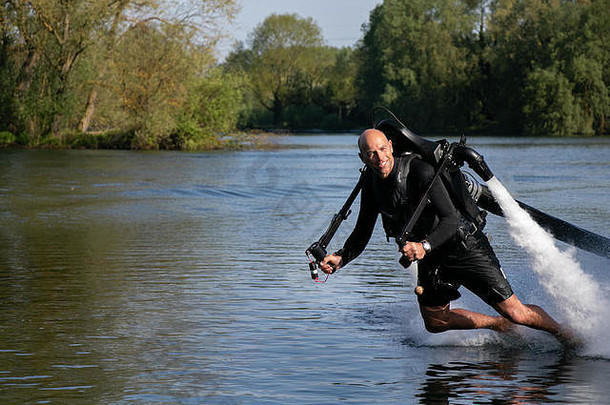 这位名为“寻刺激者”的运动员被绑在喷气式列夫车上，悬浮在湖面上，背景是蓝天和树木。