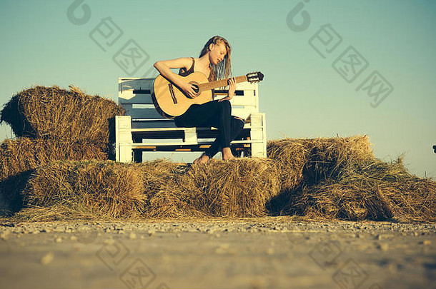 女孩在木凳上弹吉他。女吉他手演奏音乐会