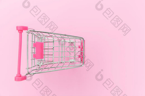 小型超市购物车，用于购物玩具，车轮独立于粉色彩色流行背景上。销售-购买-商场-市场-商店-消费者概念。拷贝空间