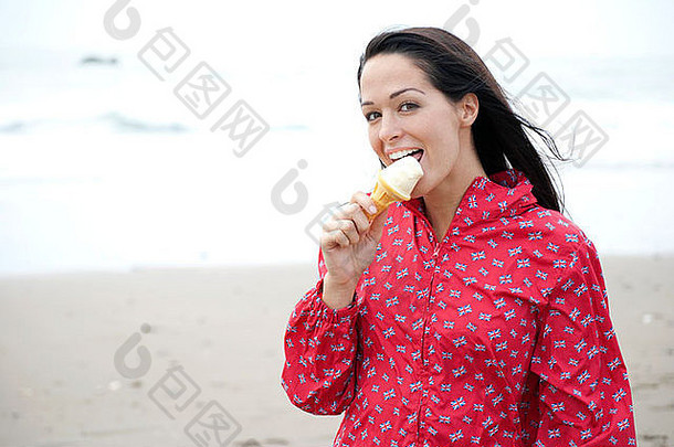 穿着联合杰克雨衣在海滩上舔冰淇淋的女人