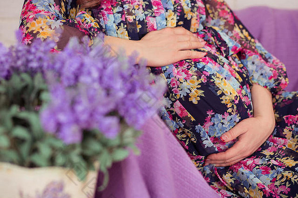 怀孕了夫人女人摆姿势坐着沙发窟紫罗兰色的班克特关闭花束薰衣草春天野生花穿色彩鲜艳的时尚的衣服
