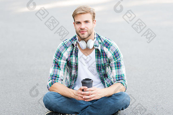 大学生活。生活平衡。幸福和健康。休息时间喝咖啡。男人坐在地上喝咖啡。放松和充电。休息时玩得开心。男生无忧无虑，喜欢在户外喝咖啡。