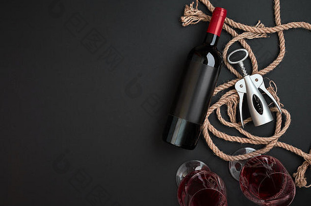 红葡萄酒瓶，两个玻璃杯和黑色背景的开瓶器。具有空间的俯视图