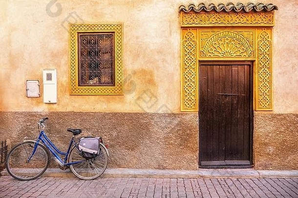 摩洛哥老房子外部的街景，木<strong>门</strong>，精美的金色窗户和<strong>门</strong>框，前面停着一辆自行车。