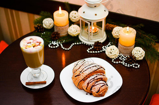 桌上有一杯带棉花糖和圣诞装饰的拿铁咖啡。
