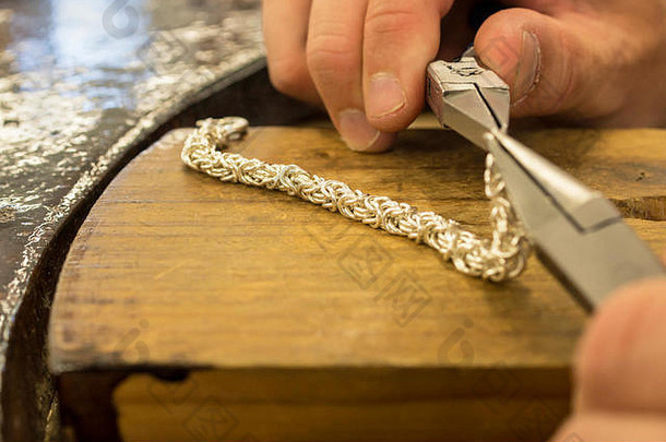 在前景中用男人手持工具制作银珠宝工艺品