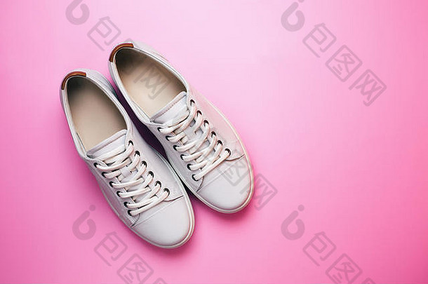 白色时尚的运动鞋粉红色的柔和的背景前面视图最小的概念