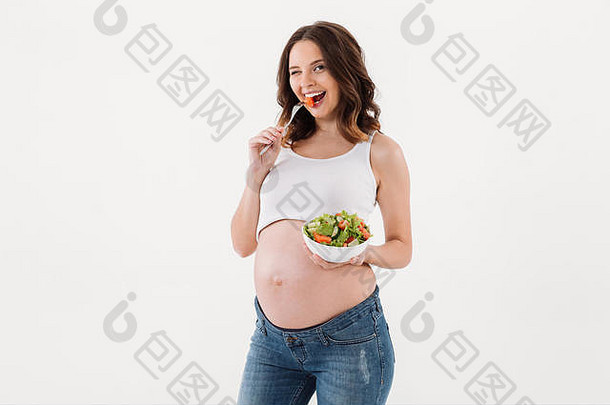 照片快乐的怀孕了女人站孤立的吃维生素沙拉白色背景相机