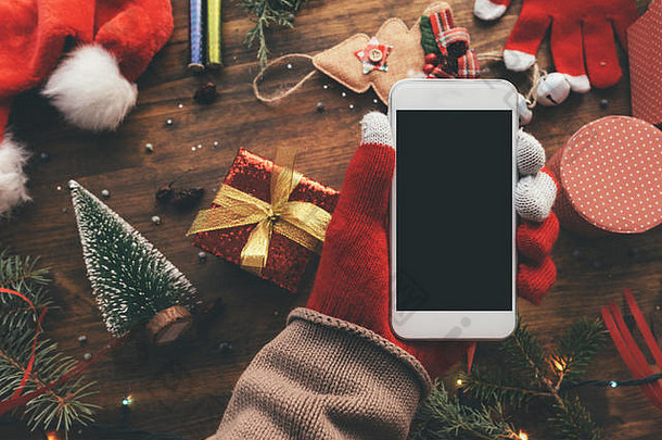 手持智能手机，用于圣诞季模拟，背景为节日装饰。
