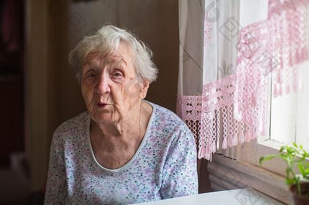 一位老妇人正坐在她家的桌子旁。