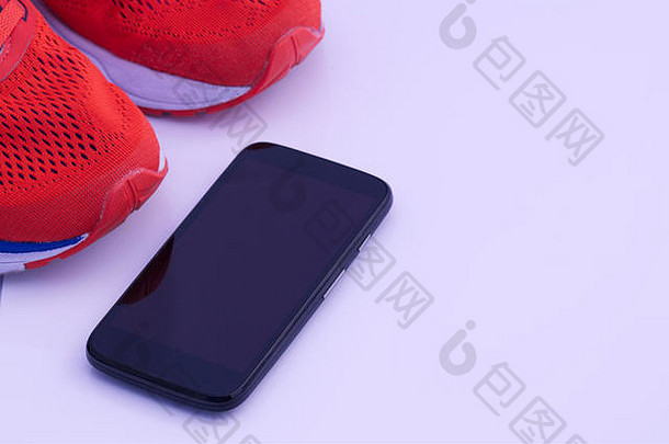 充满活力的橙色跑步训练鞋，黑色手机与白色背景隔离。跑，跑概念