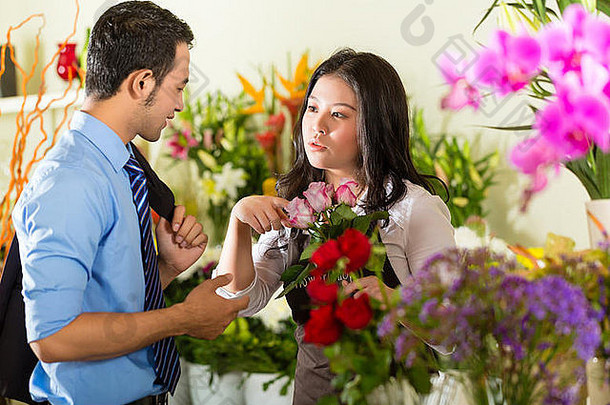 友好的亚洲花商或花店女售货员建议顾客