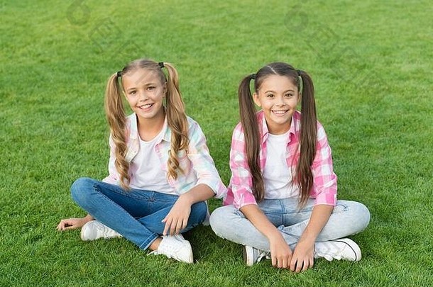 孩子是未来。小孩子坐在绿草上。快乐的孩子们在户外玩得很开心。看起来很时尚的小孩。休闲风格潮流。快乐的童年。国际儿童节。