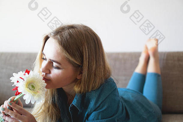 有吸引力的年轻的女人嗅探花束花说谎沙发上