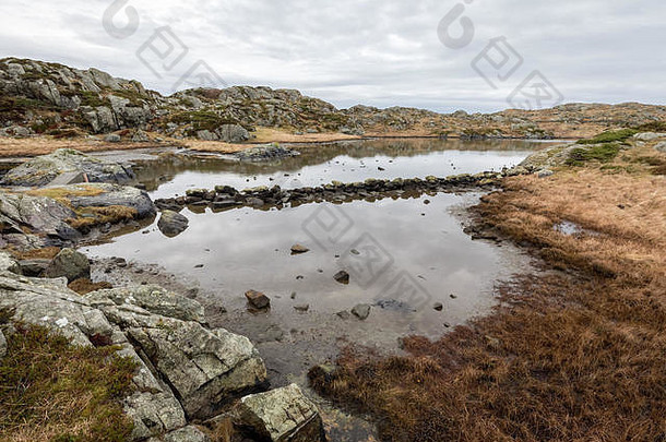 挪威豪格松岛罗瓦尔群岛小径旁的池塘。石头在水中形成一<strong>条通道</strong>。
