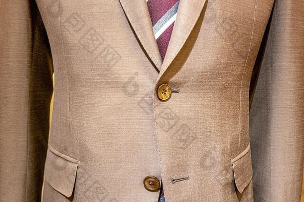 米色男式套装，红色条纹领带收拢，单扣未扣