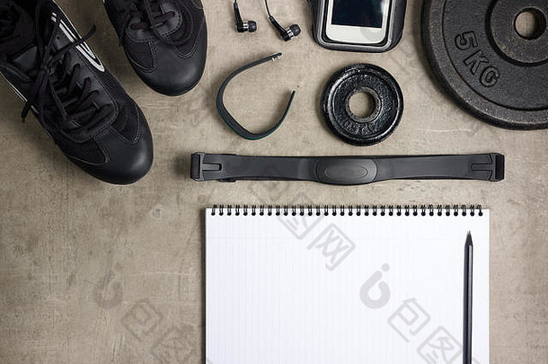 特写镜头铺设地板上黑色的运动鞋耳机健身跟踪器瓶水重量板打开笔记本笔